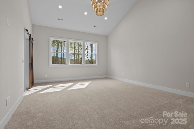 spare room with a barn door, carpet flooring, visible vents, and recessed lighting