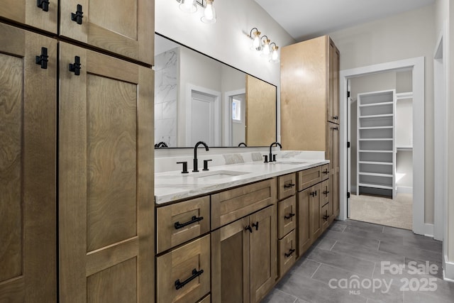 full bathroom with double vanity, a spacious closet, and a sink