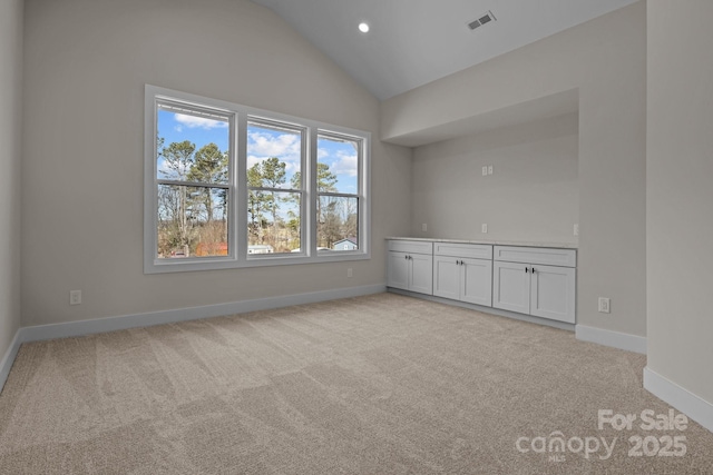 unfurnished room featuring light carpet, vaulted ceiling, visible vents, and baseboards