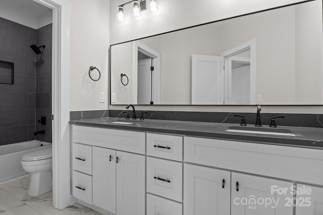 full bath with marble finish floor, double vanity, a sink, and toilet