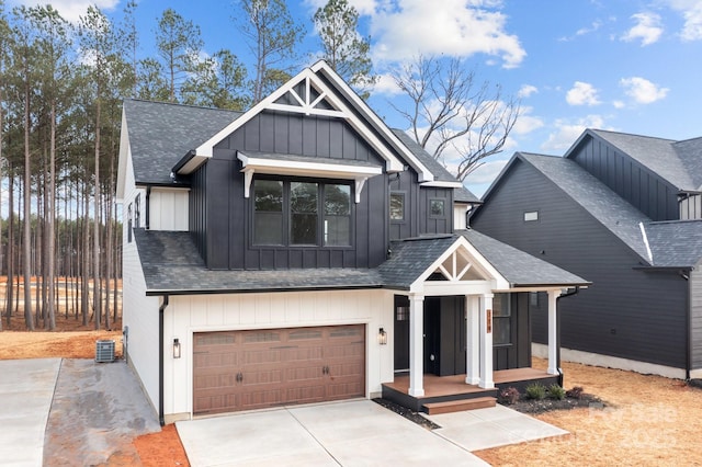 modern farmhouse featuring central air condition unit, a porch, board and batten siding, a garage, and driveway