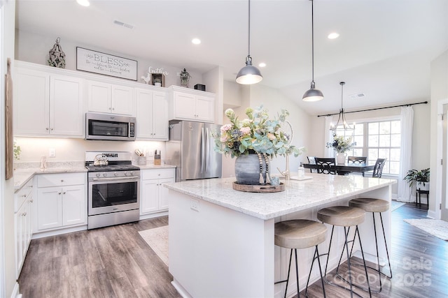 kitchen with visible vents, wood finished floors, a center island, white cabinetry, and appliances with stainless steel finishes