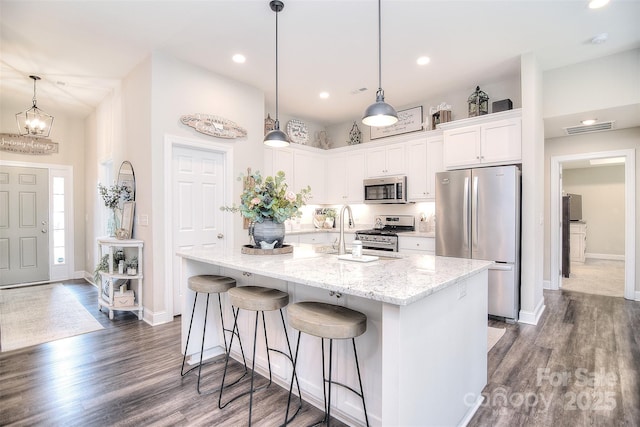 kitchen featuring a sink, a kitchen breakfast bar, dark wood-style floors, stainless steel appliances, and white cabinets