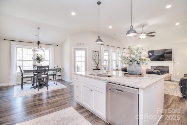 kitchen featuring wood finished floors, lofted ceiling, a sink, stainless steel dishwasher, and open floor plan