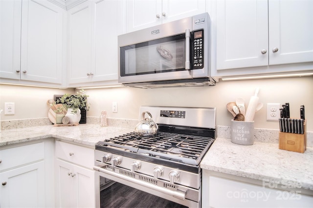 kitchen featuring wood finished floors, appliances with stainless steel finishes, white cabinetry, and light stone countertops