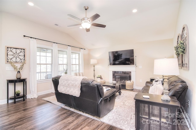 living room featuring wood finished floors, visible vents, baseboards, lofted ceiling, and a fireplace