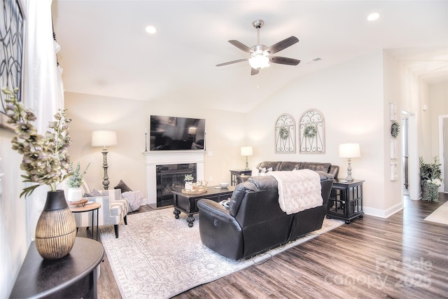 living area featuring wood finished floors, baseboards, visible vents, a premium fireplace, and vaulted ceiling