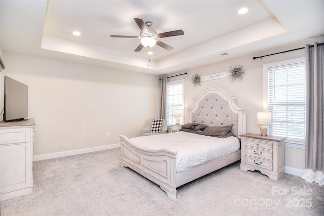 bedroom featuring visible vents, a tray ceiling, recessed lighting, baseboards, and light colored carpet