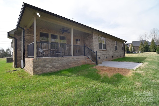 rear view of property featuring a ceiling fan, a lawn, brick siding, and crawl space