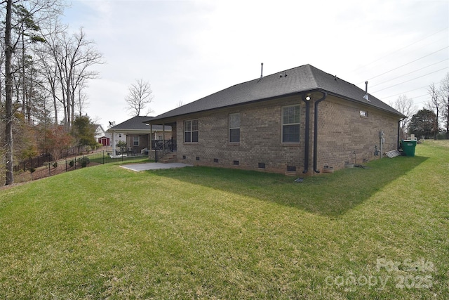 back of property with brick siding, fence, a patio area, a yard, and crawl space