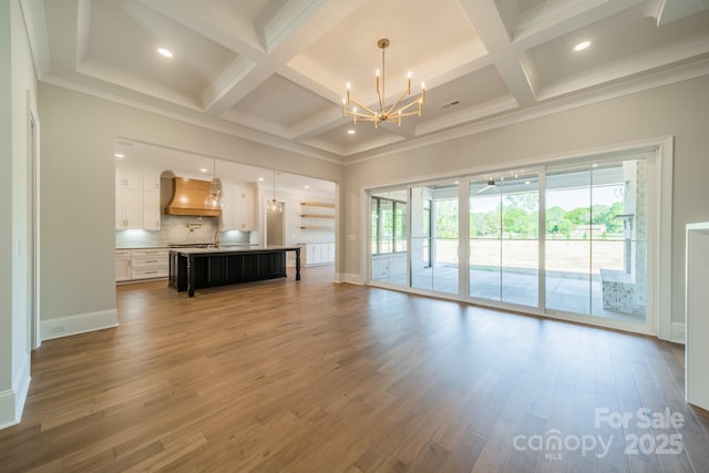 living room featuring coffered ceiling, wood finished floors, an inviting chandelier, and recessed lighting