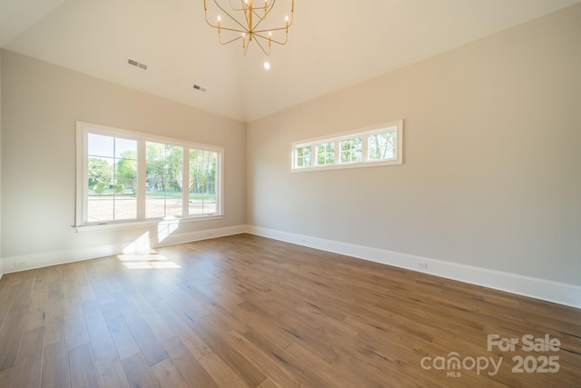 unfurnished room featuring baseboards, high vaulted ceiling, an inviting chandelier, and wood finished floors