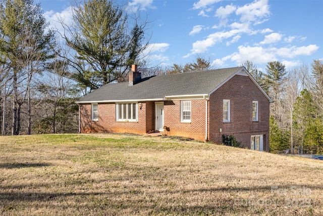 ranch-style house featuring brick siding, a chimney, and a front yard