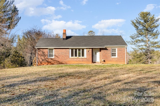 ranch-style home with brick siding, a chimney, a shingled roof, and a front lawn