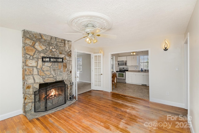 unfurnished living room with a textured ceiling, a fireplace, and wood finished floors