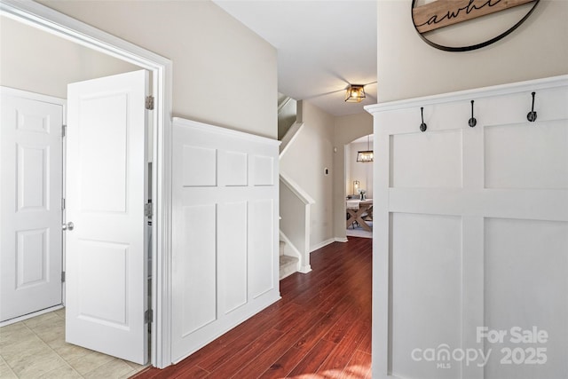 hallway with arched walkways, wood finished floors, and stairs