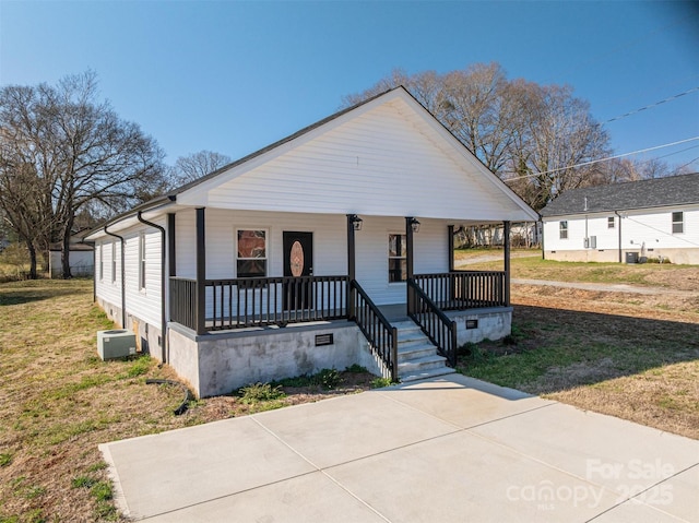 view of front facade with cooling unit, covered porch, crawl space, and a front yard