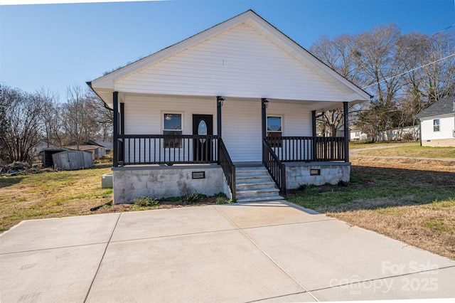bungalow-style house with a front lawn, an outbuilding, covered porch, and crawl space