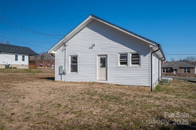 rear view of property featuring cooling unit and a lawn
