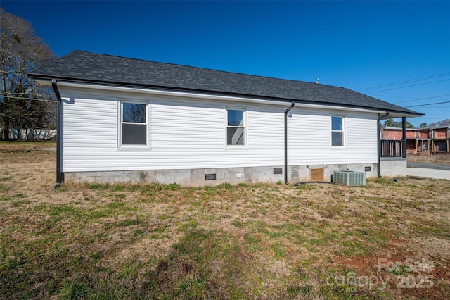 rear view of house with crawl space, central air condition unit, a shingled roof, and a yard