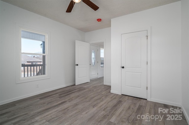 unfurnished bedroom with ceiling fan, baseboards, and wood finished floors