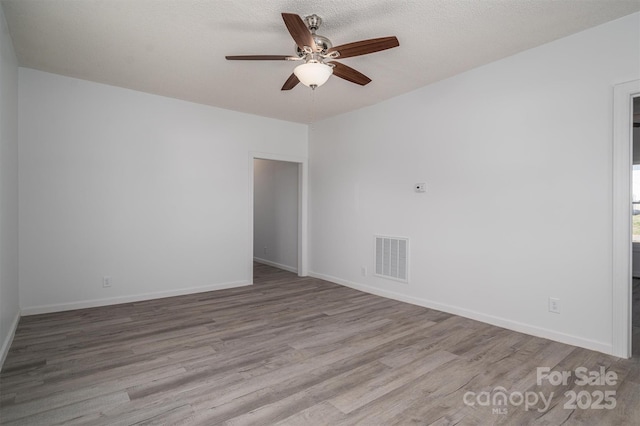 empty room with baseboards, visible vents, and wood finished floors