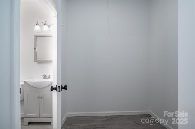 bathroom featuring baseboards, wood finished floors, and vanity