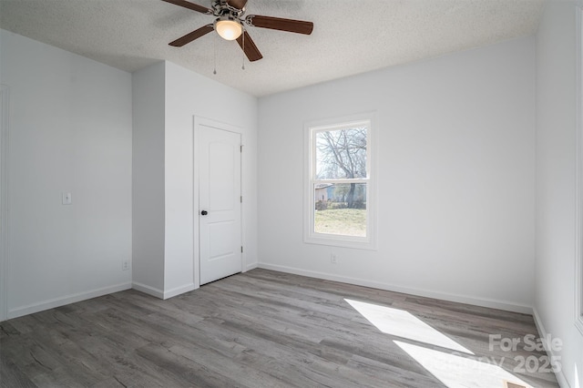 unfurnished room featuring ceiling fan, a textured ceiling, baseboards, and wood finished floors