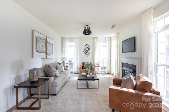 living area featuring visible vents and a glass covered fireplace