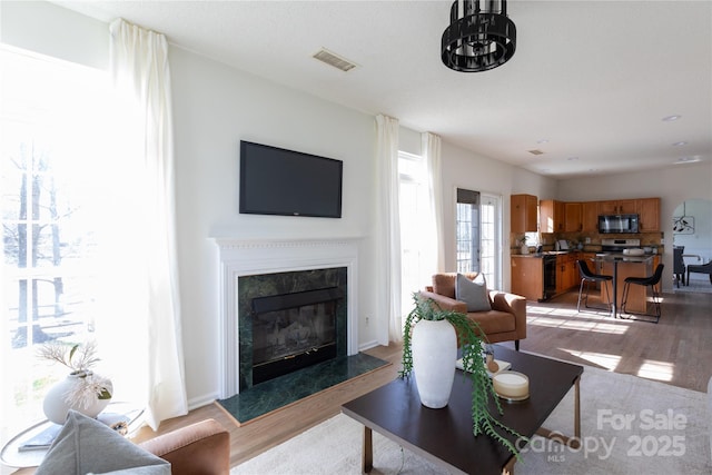 living area with light wood-style flooring, a fireplace, and visible vents