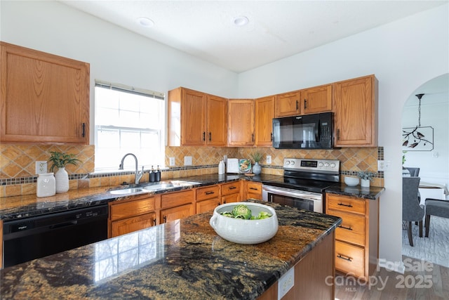 kitchen with tasteful backsplash, dark stone counters, a sink, and black appliances