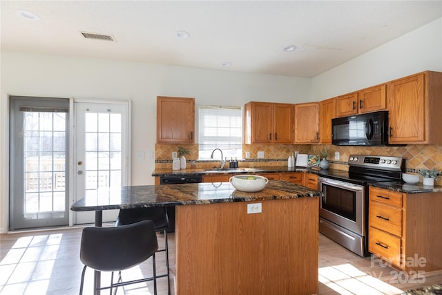 kitchen with visible vents, a center island, stainless steel range with electric stovetop, black microwave, and a sink