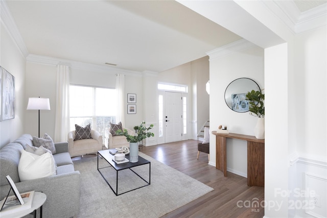 living area with crown molding, stairway, baseboards, and wood finished floors