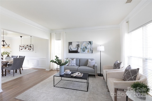 living area featuring plenty of natural light, ornamental molding, a decorative wall, and wood finished floors