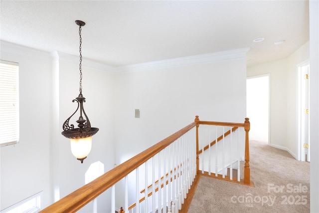 hallway featuring carpet floors, ornamental molding, and an upstairs landing