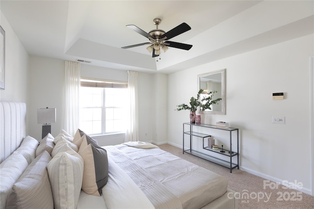 bedroom featuring a raised ceiling, light colored carpet, visible vents, and baseboards