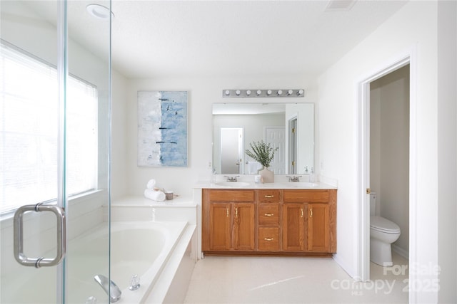 full bath featuring toilet, a garden tub, double vanity, and a sink