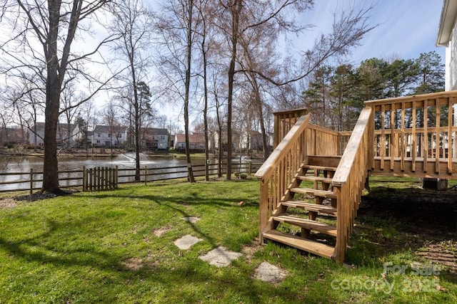 view of yard featuring stairway, fence, and a deck with water view