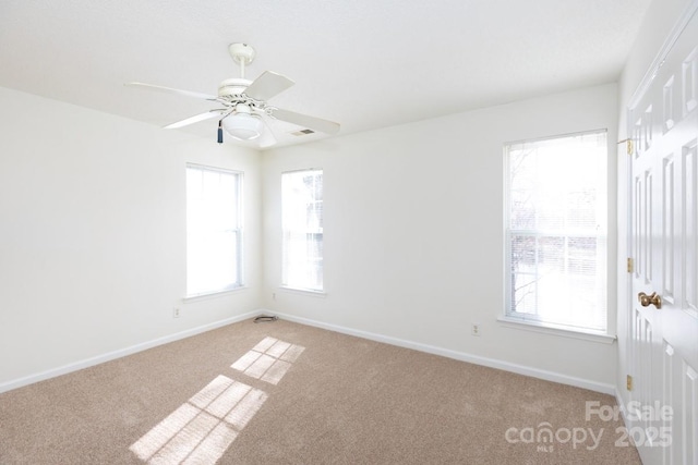 spare room featuring visible vents, baseboards, a ceiling fan, and light colored carpet