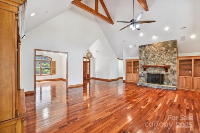 unfurnished living room featuring high vaulted ceiling, wood finished floors, ceiling fan, a fireplace, and visible vents