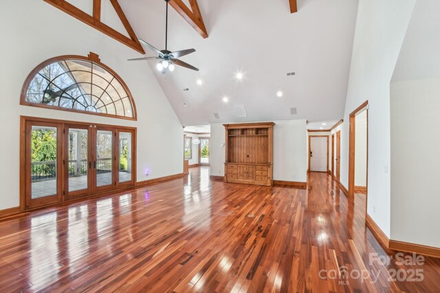 unfurnished living room featuring french doors, baseboards, a ceiling fan, hardwood / wood-style floors, and high vaulted ceiling