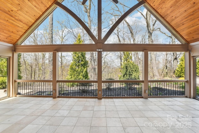 unfurnished sunroom featuring a wealth of natural light, wooden ceiling, tile patterned flooring, and high vaulted ceiling
