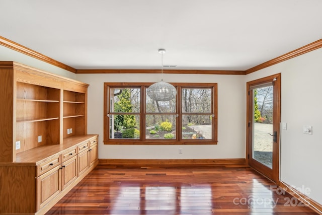 unfurnished dining area featuring dark wood-type flooring, crown molding, and baseboards
