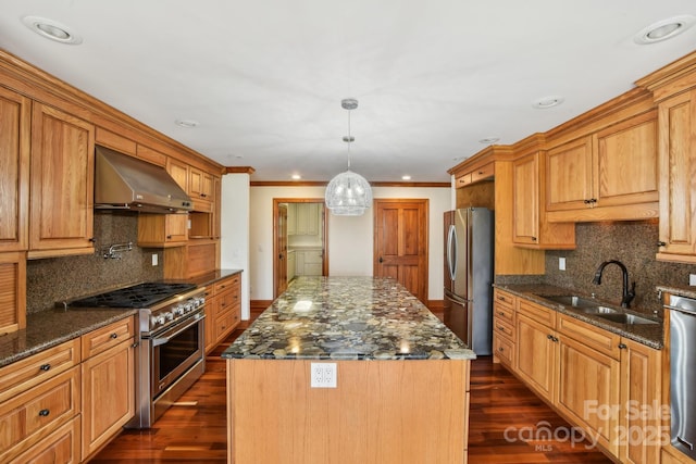 kitchen featuring stainless steel appliances, a sink, tasteful backsplash, extractor fan, and a kitchen island