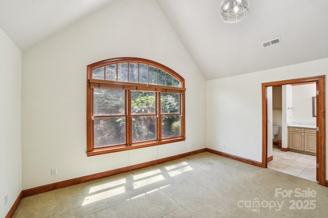 unfurnished bedroom featuring baseboards, ensuite bath, visible vents, and light colored carpet