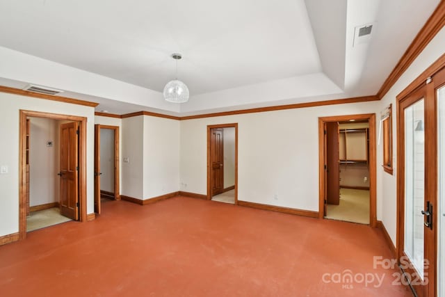 unfurnished bedroom featuring a walk in closet, a tray ceiling, carpet, baseboards, and visible vents