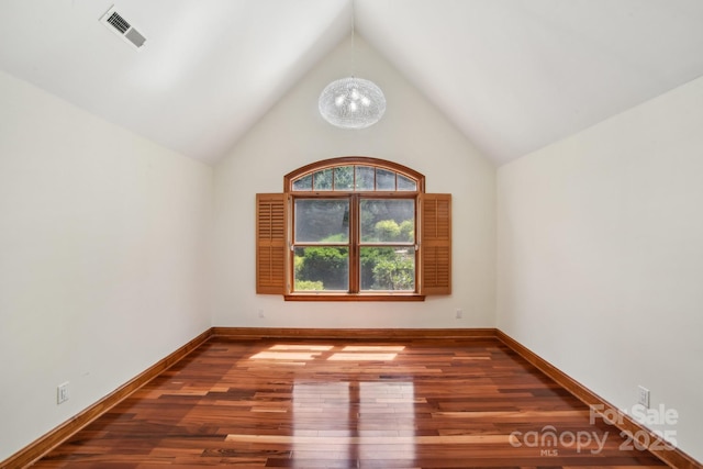 spare room featuring an inviting chandelier, wood finished floors, visible vents, baseboards, and high vaulted ceiling