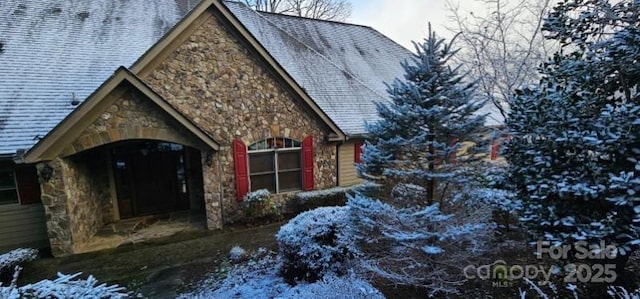 view of snow covered exterior featuring stone siding