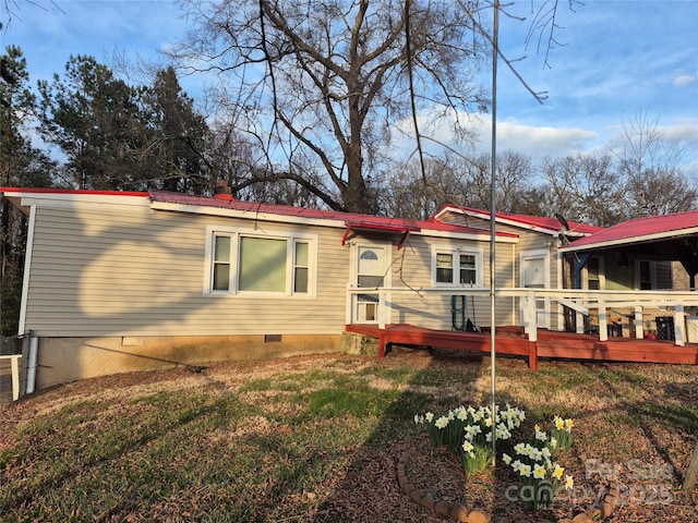 rear view of property featuring a yard, crawl space, metal roof, and a wooden deck