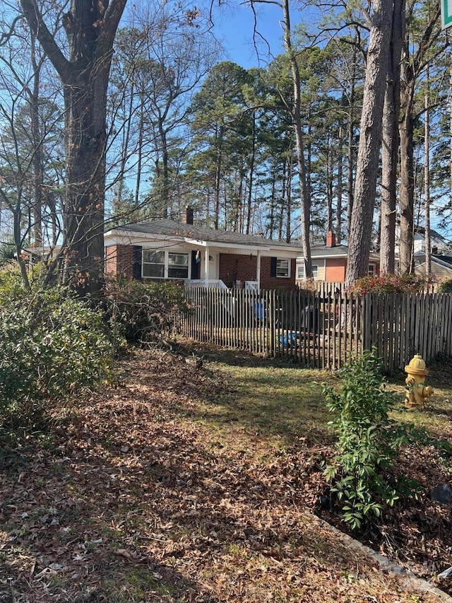 exterior space with brick siding, a fenced front yard, and a chimney